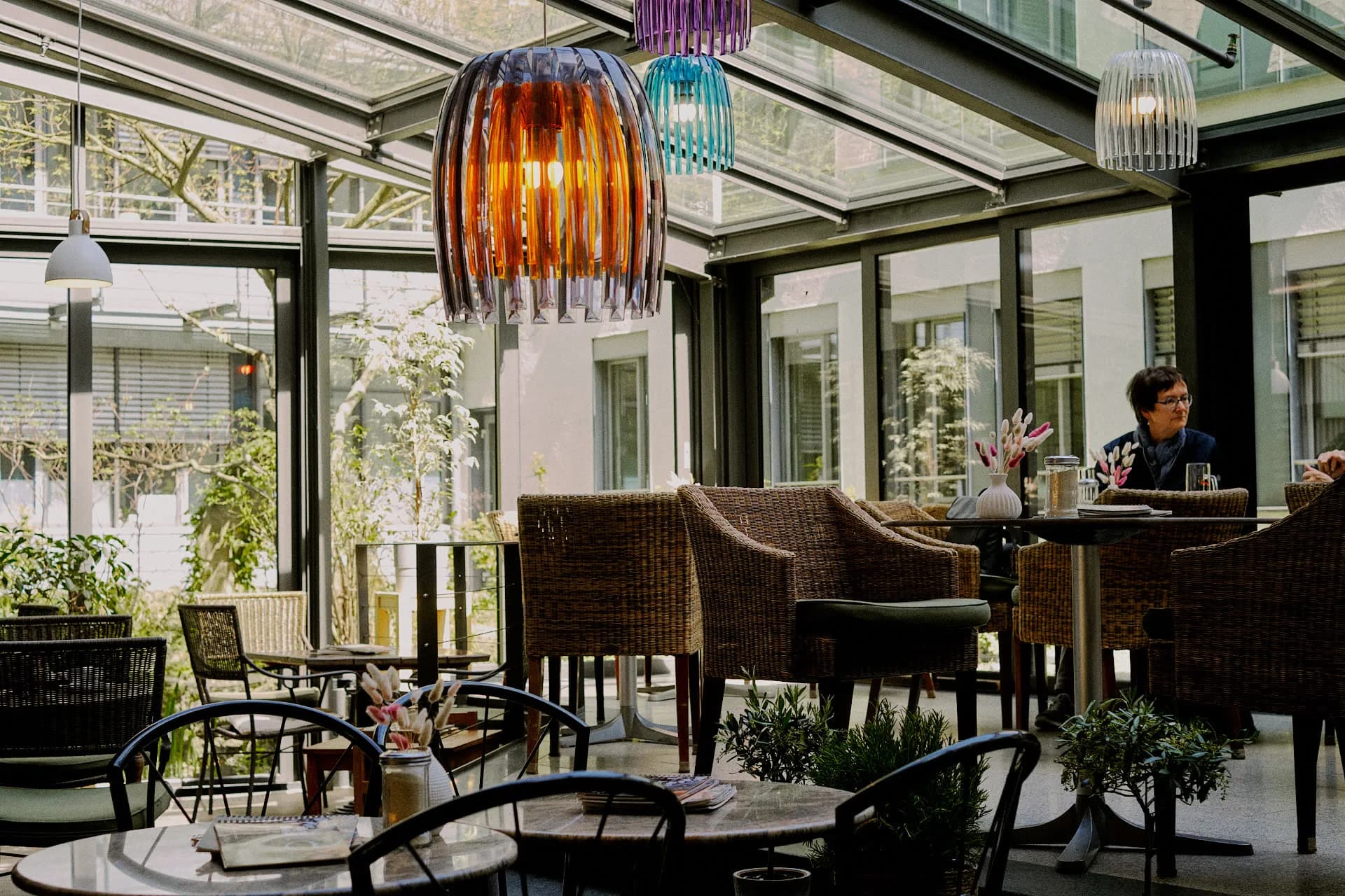 Wintergarten mit bunten Pendant-Lampen und gemütlichen Korbsesseln